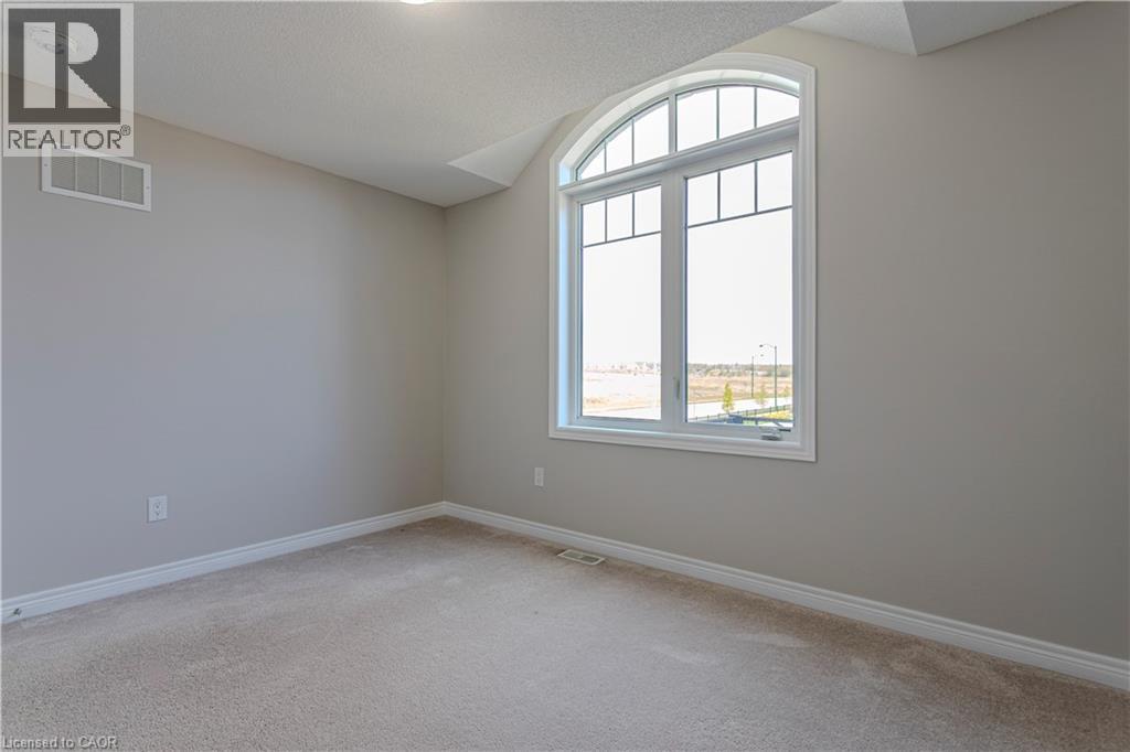 Arched window with divided lites, neutral wall paint, textured carpeting, and white baseboards - 3896 Tufgar Crescent, Burlington, ON - Indoor Photo Showing Other Room