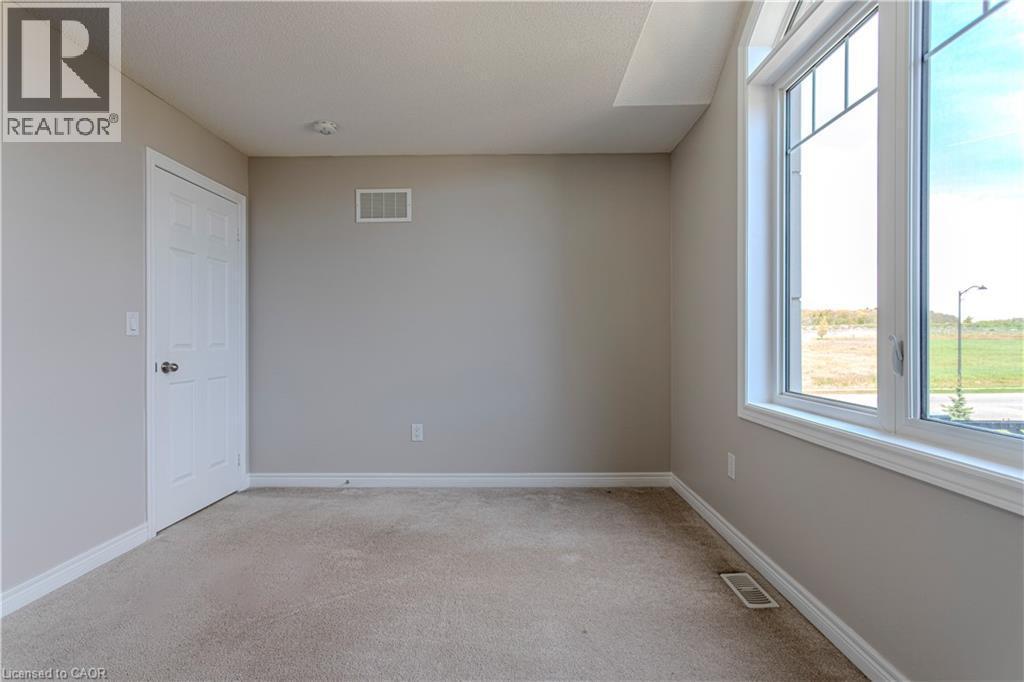 Neutral-toned room featuring a large window with white trim, light beige wall paint, plush carpeting, a white paneled door, and ceiling-mounted lighting - 3896 Tufgar Crescent, Burlington, ON - Indoor Photo Showing Other Room