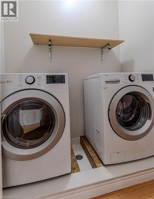 Dedicated laundry area featuring a wall-mounted shelving unit with wood-finish surface, light gray walls, and white baseboards - 3896 Tufgar Crescent, Burlington, ON - Indoor Photo Showing Laundry Room