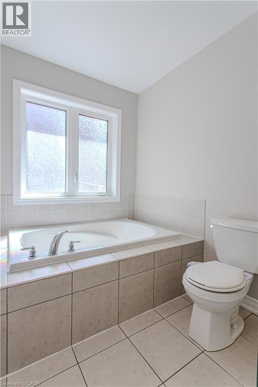 Built-in soaking tub with chrome fixtures, surrounded by neutral-toned tiled surfaces - 3896 Tufgar Crescent, Burlington, ON - Indoor Photo Showing Bathroom