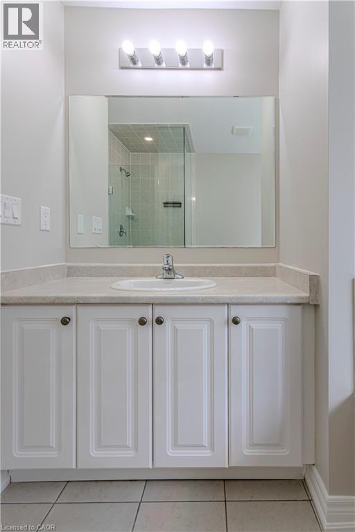 Bathroom vanity featuring an integrated sink, laminate countertop, white paneled cabinetry with dark hardware, a large mirror, and overhead strip lighting - 3896 Tufgar Crescent, Burlington, ON - Indoor Photo Showing Bathroom