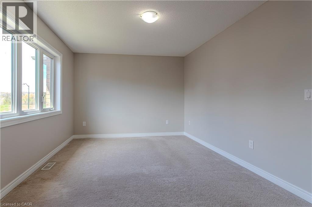 Carpeted room featuring neutral wall paint, white trim, a large multi-pane window, and a ceiling-mounted light fixture - 3896 Tufgar Crescent, Burlington, ON - Indoor Photo Showing Other Room