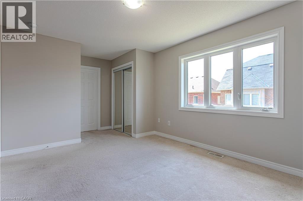 Spacious room featuring neutral paint, light-colored carpeting, a large three-pane window, and a mirrored closet - 3896 Tufgar Crescent, Burlington, ON - Indoor Photo Showing Other Room