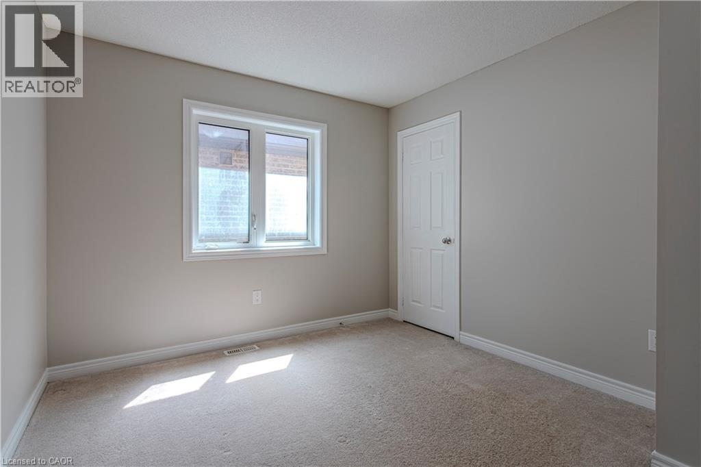 Carpeted room featuring a white-framed window, neutral painted walls, white trim, and a paneled interior door - 3896 Tufgar Crescent, Burlington, ON - Indoor Photo Showing Other Room