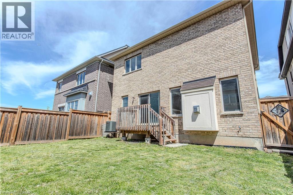 Rear exterior featuring a brick facade, private wooden fence, and a raised wooden deck with stairs to the yard - 3896 Tufgar Crescent, Burlington, ON - Outdoor