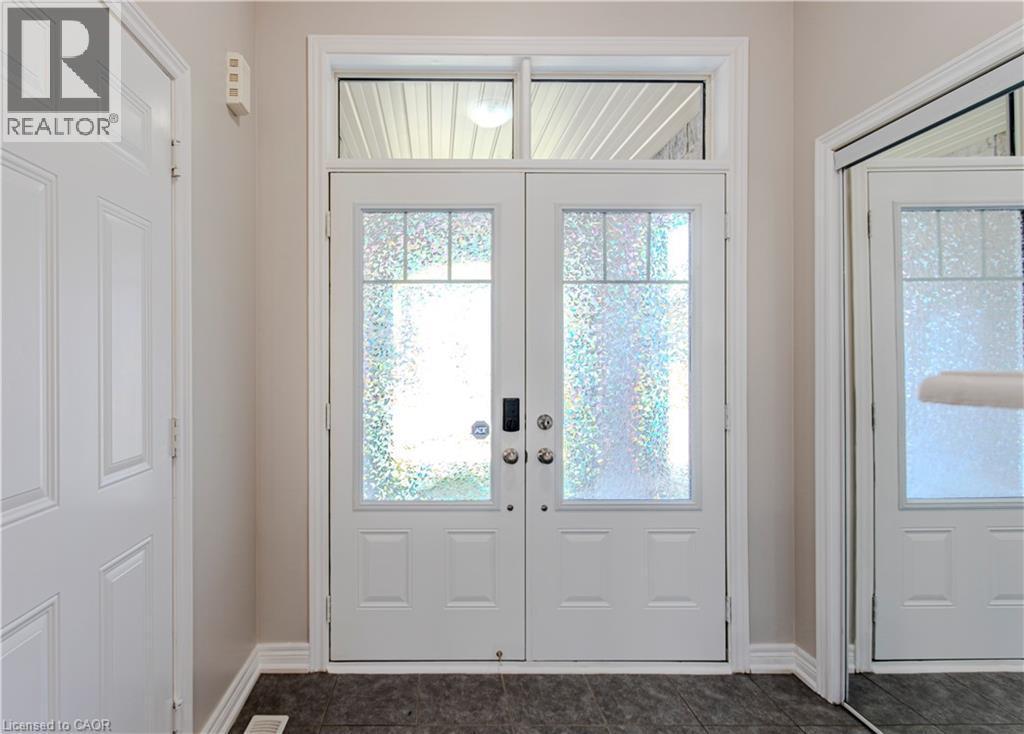 Double entry doors with patterned glass inserts and a transom window, complemented by dark tile flooring and light-toned walls - 3896 Tufgar Crescent, Burlington, ON - Indoor Photo Showing Other Room