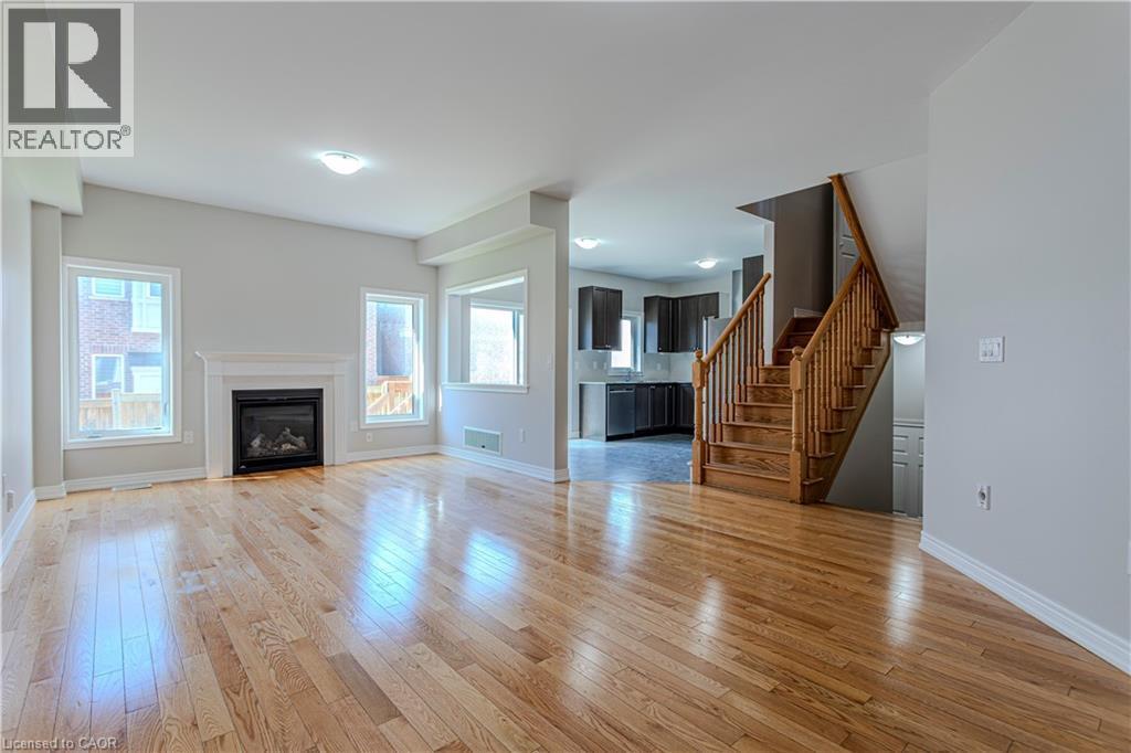 Open-concept living area featuring wood-finish flooring, a contemporary fireplace with a classic mantel, and multiple windows - 3896 Tufgar Crescent, Burlington, ON - Indoor Photo Showing Living Room With Fireplace