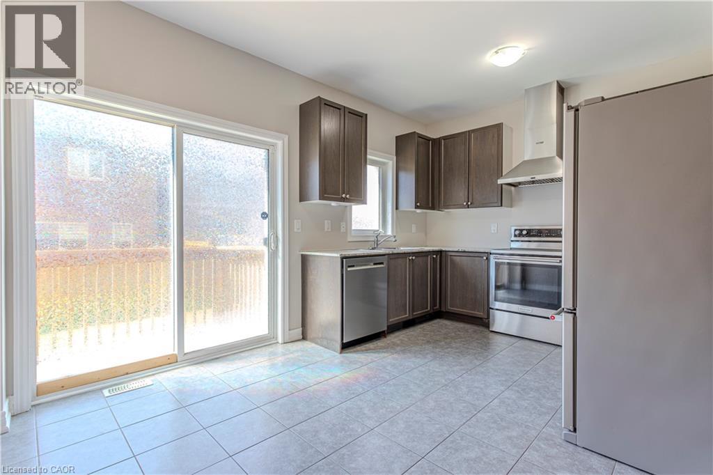 Kitchen featuring dark wood-finish cabinetry, stainless steel appliances, and light-toned countertops - 3896 Tufgar Crescent, Burlington, ON - Indoor Photo Showing Kitchen