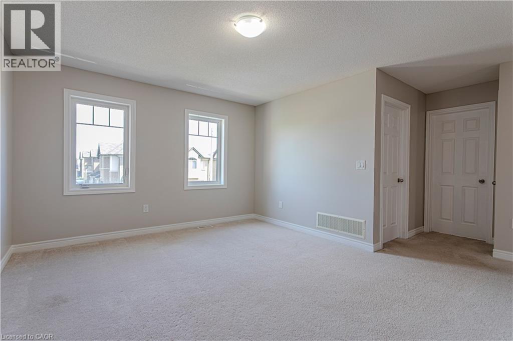 Expansive room featuring light-colored carpeting, two paneled doors, and two windows with white trim - 3896 Tufgar Crescent, Burlington, ON - Indoor Photo Showing Other Room
