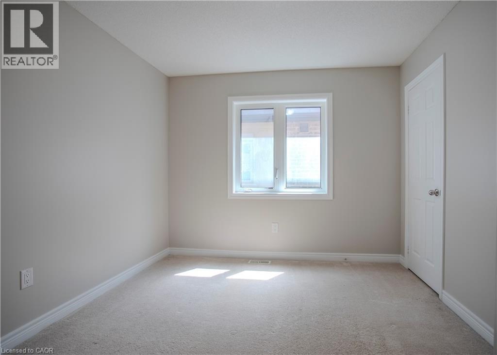 Carpeted room featuring a white-framed window, neutral painted walls, white trim, and a white paneled door with a silver-toned knob - 3896 Tufgar Crescent, Burlington, ON - Indoor Photo Showing Other Room