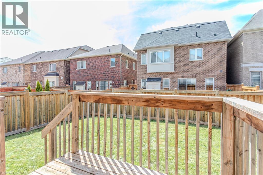 Elevated wood deck with railings overlooking a fenced yard featuring green lawn and a brick exterior structure with a bay window - 3896 Tufgar Crescent, Burlington, ON - Outdoor With Deck Patio Veranda With Exterior