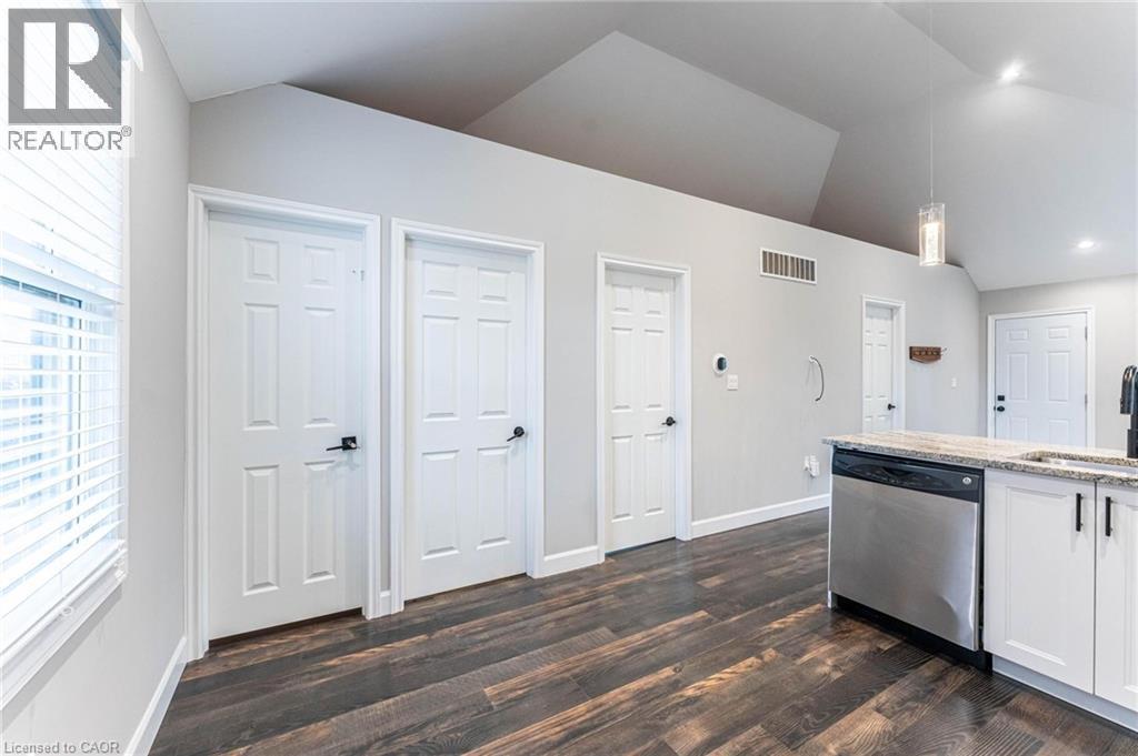 Kitchen featuring white cabinetry, light stone counters, stainless steel dishwasher, pendant lighting, and healthy amount of natural light - 222 Kensington Avenue N, Hamilton, ON - Indoor Photo Showing Other Room