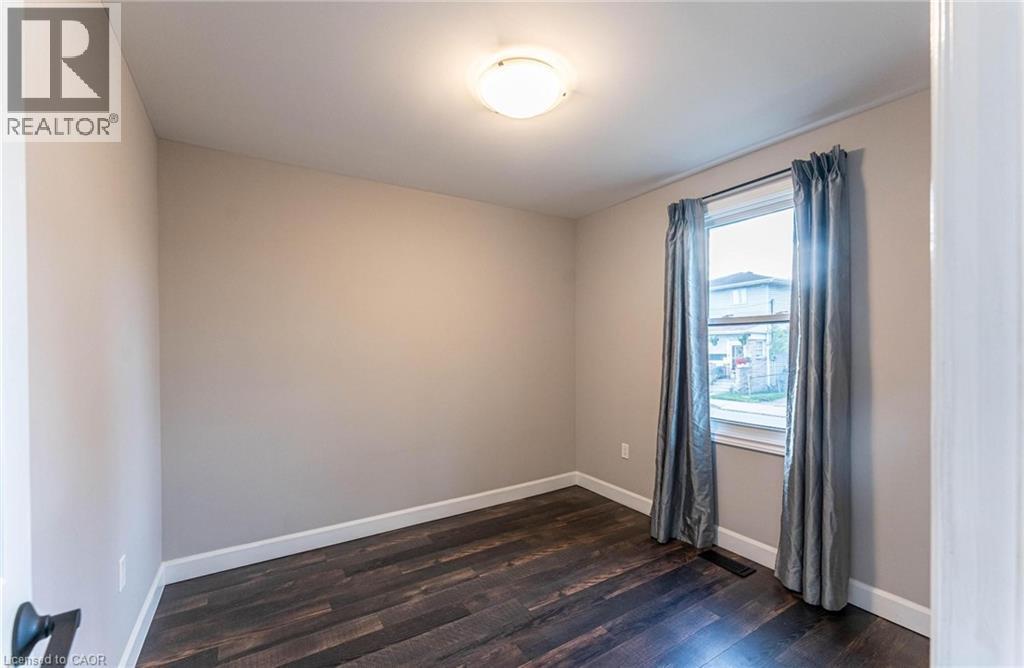 Empty room with baseboards and dark wood-style floors - 222 Kensington Avenue N, Hamilton, ON - Indoor Photo Showing Other Room