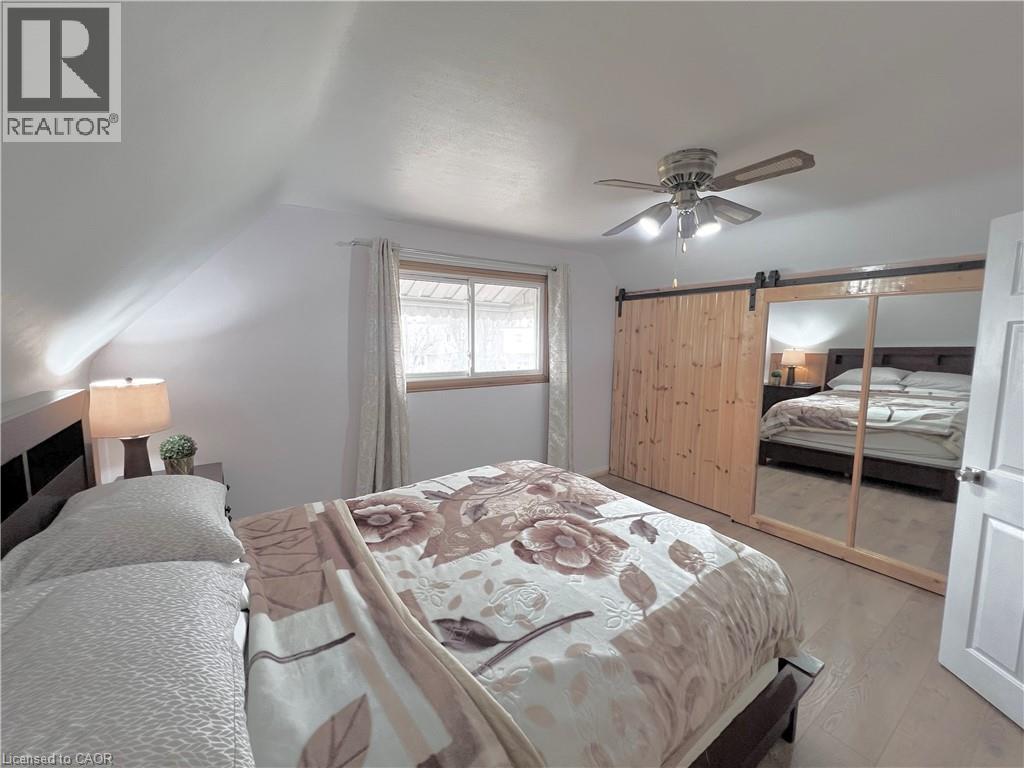 Sloped ceiling room featuring wood-finish flooring, a window with natural light, and a ceiling fan with integrated lighting - 56 Eastvale Place, Hamilton, ON - Indoor Photo Showing Bedroom