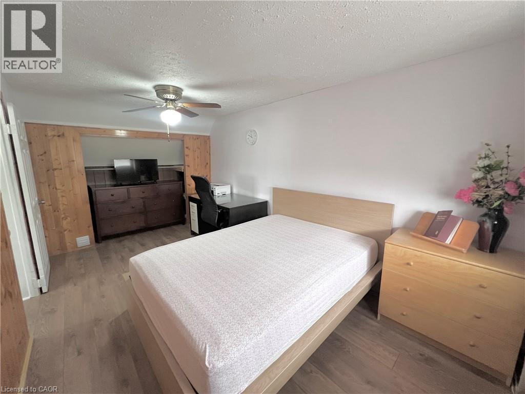 Room featuring wood-finish flooring, a ceiling fan with integrated lighting, and white painted walls - 56 Eastvale Place, Hamilton, ON - Indoor Photo Showing Bedroom