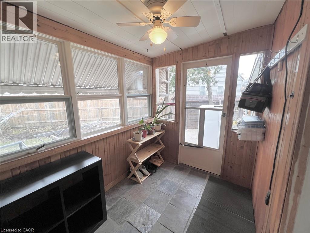 Enclosed sunroom featuring natural wood paneling, multiple windows, a ceiling fan with integrated lighting, a full-light door, and slate tile flooring - 56 Eastvale Place, Hamilton, ON - Indoor Photo Showing Other Room