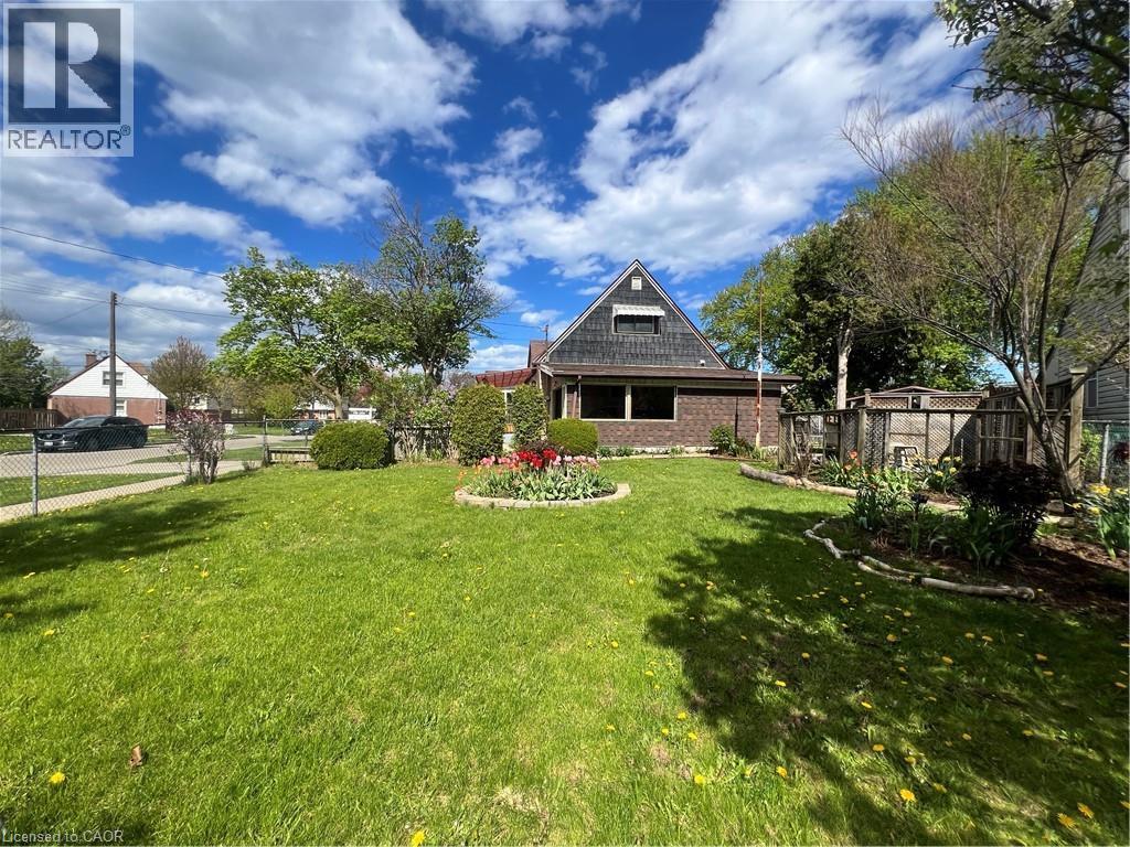 Expansive front yard featuring a manicured lawn, established landscaping, and mature trees - 56 Eastvale Place, Hamilton, ON - Outdoor