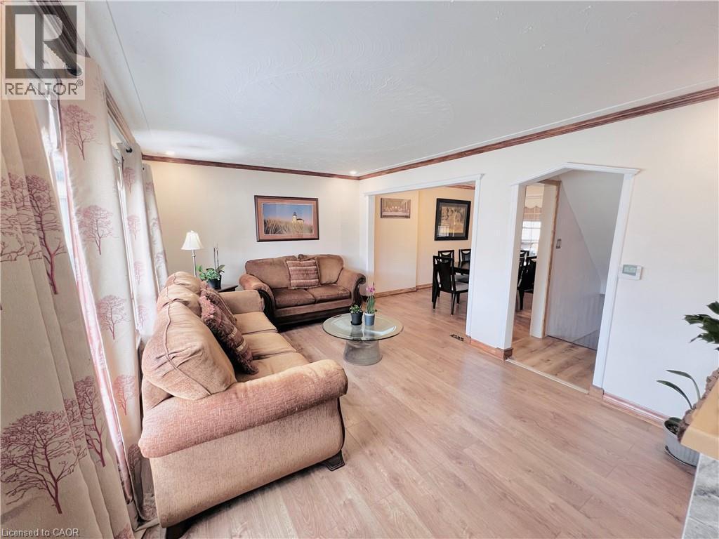 Light wood-finish flooring provides a bright base for this living area with crown molding - 56 Eastvale Place, Hamilton, ON - Indoor Photo Showing Living Room