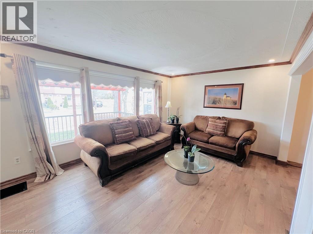 Living area featuring light wood-finish flooring, a wide bay window, and crown molding - 56 Eastvale Place, Hamilton, ON - Indoor Photo Showing Living Room