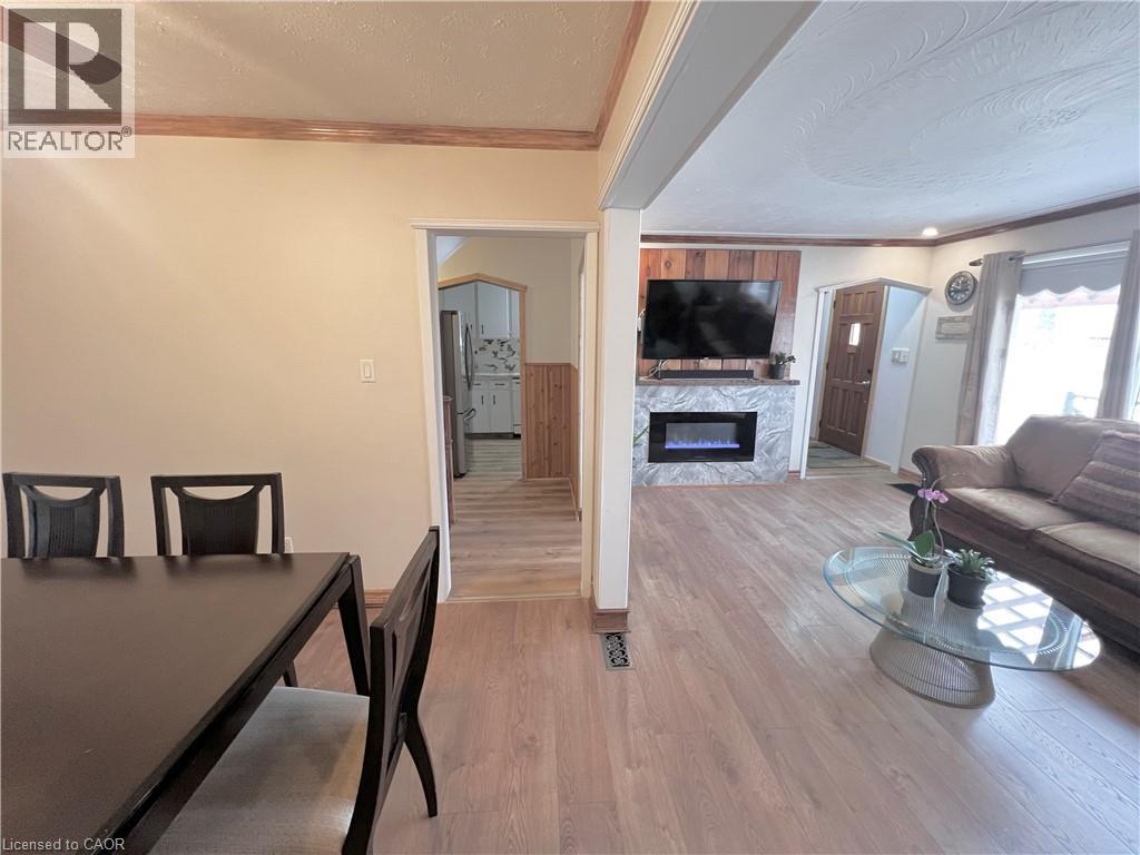Living area featuring wood-finish flooring and a fireplace with a stone-finish surround - 56 Eastvale Place, Hamilton, ON - Indoor Photo Showing Other Room With Fireplace