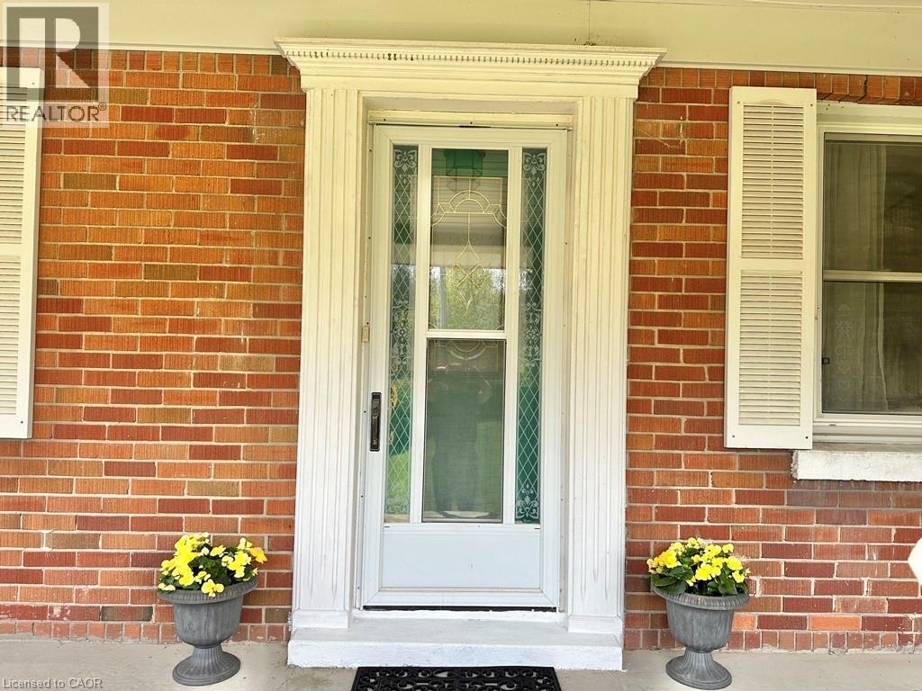 Brick exterior entry featuring a storm door with decorative glass inserts, fluted pilasters, and dentil molding - 165 Highway 6, Simcoe, ON - Outdoor With Exterior