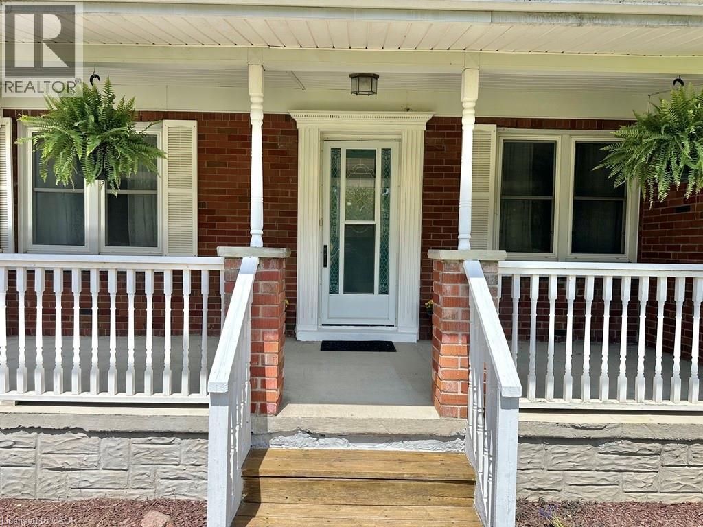 Brick facade residence featuring a covered front porch with white railing - 165 Highway 6, Simcoe, ON - Outdoor With Deck Patio Veranda