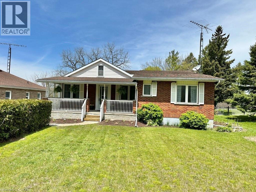 Brick and siding exterior featuring a covered front porch with white railings and steps - 165 Highway 6, Simcoe, ON - Outdoor With Deck Patio Veranda