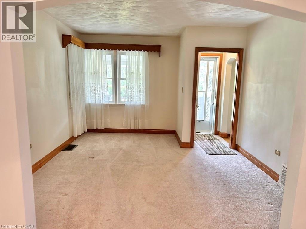 Carpeted living space with a large window featuring natural wood trim and valance - 165 Highway 6, Simcoe, ON - Indoor Photo Showing Other Room