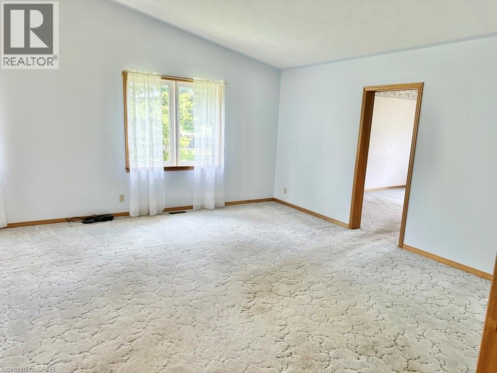 Open room featuring light-toned walls, vaulted ceiling, and patterned carpeting - 165 Highway 6, Simcoe, ON - Indoor Photo Showing Other Room