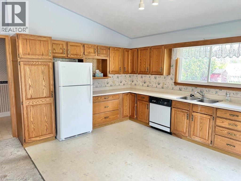 Kitchen featuring wood cabinetry, light-toned countertops, and a double-basin stainless steel sink - 165 Highway 6, Simcoe, ON - Indoor Photo Showing Kitchen With Double Sink