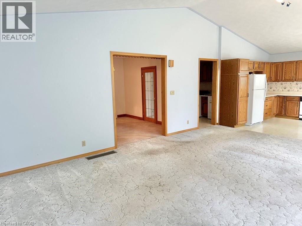 Vaulted ceilings above a carpeted living space, featuring an open doorway to a separate room with glass-paneled double doors - 165 Highway 6, Simcoe, ON - Indoor