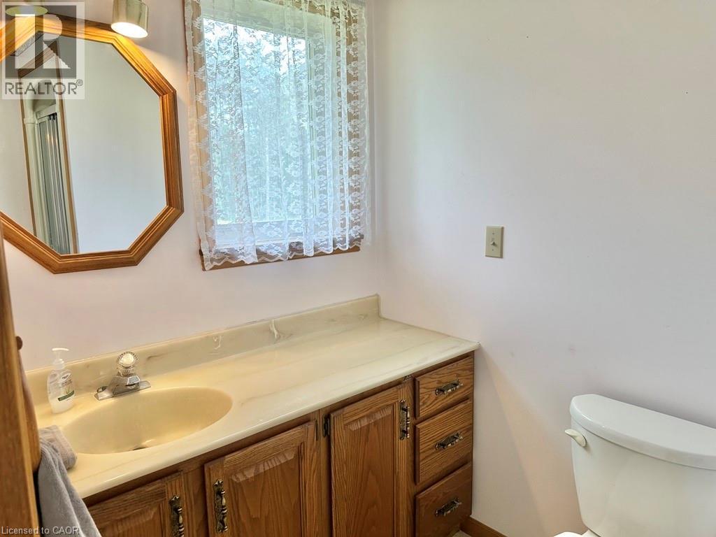 Bathroom vanity with an integrated sink, wood-finish cabinetry, and a light-toned countertop - 165 Highway 6, Simcoe, ON - Indoor Photo Showing Bathroom