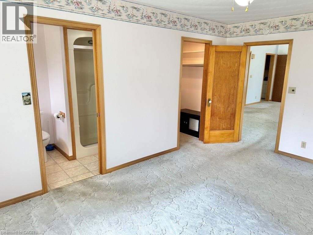 Carpeted room featuring a white ceiling with a central light fixture, a patterned wallpaper border, and light wood trim - 165 Highway 6, Simcoe, ON - Indoor Photo Showing Other Room