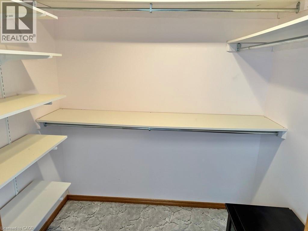 Walk-in closet featuring adjustable shelving, multiple hanging rods, and patterned carpet flooring - 165 Highway 6, Simcoe, ON - Indoor With Storage