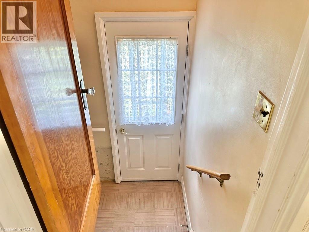 Entryway featuring a white paneled door with glass insert, wood-finish flooring, and a wall-mounted handrail - 165 Highway 6, Simcoe, ON - Indoor Photo Showing Other Room