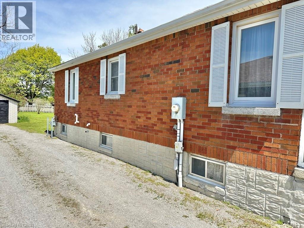 Brick exterior featuring white louvered shutters, white window trim, and a white foundation with textured block - 165 Highway 6, Simcoe, ON - Outdoor With Exterior