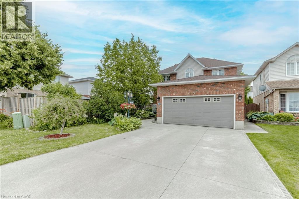 View of front facade with brick siding, concrete driveway, and an attached garage - 32 Vineberg Drive, Hamilton, ON - Outdoor