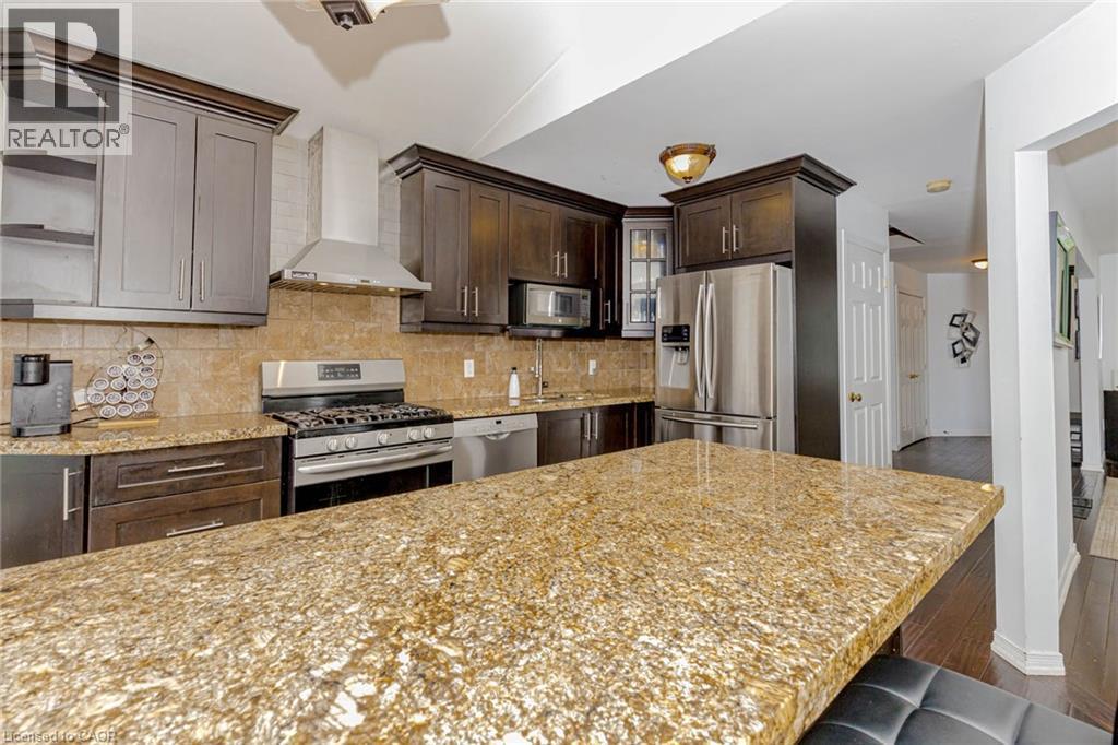 Kitchen with stainless steel appliances, decorative backsplash, open shelves, dark wood-style floors, and dark wood finish cabinetry - 32 Vineberg Drive, Hamilton, ON - Indoor Photo Showing Kitchen With Upgraded Kitchen