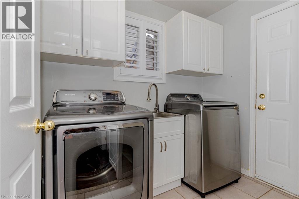 Laundry area featuring washer and clothes dryer, cabinet space, and light tile patterned flooring - 32 Vineberg Drive, Hamilton, ON - Indoor Photo Showing Laundry Room