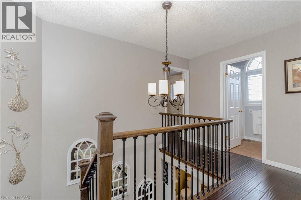 Hall with an upstairs landing, a textured ceiling, hanging lights, and wood finished floors - 32 Vineberg Drive, Hamilton, ON - Indoor Photo Showing Other Room