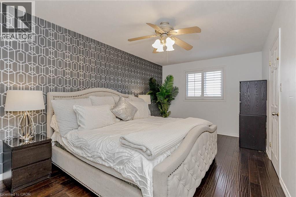 Bedroom featuring an accent wall, wallpapered walls, dark wood-type flooring, and a ceiling fan - 32 Vineberg Drive, Hamilton, ON - Indoor Photo Showing Bedroom