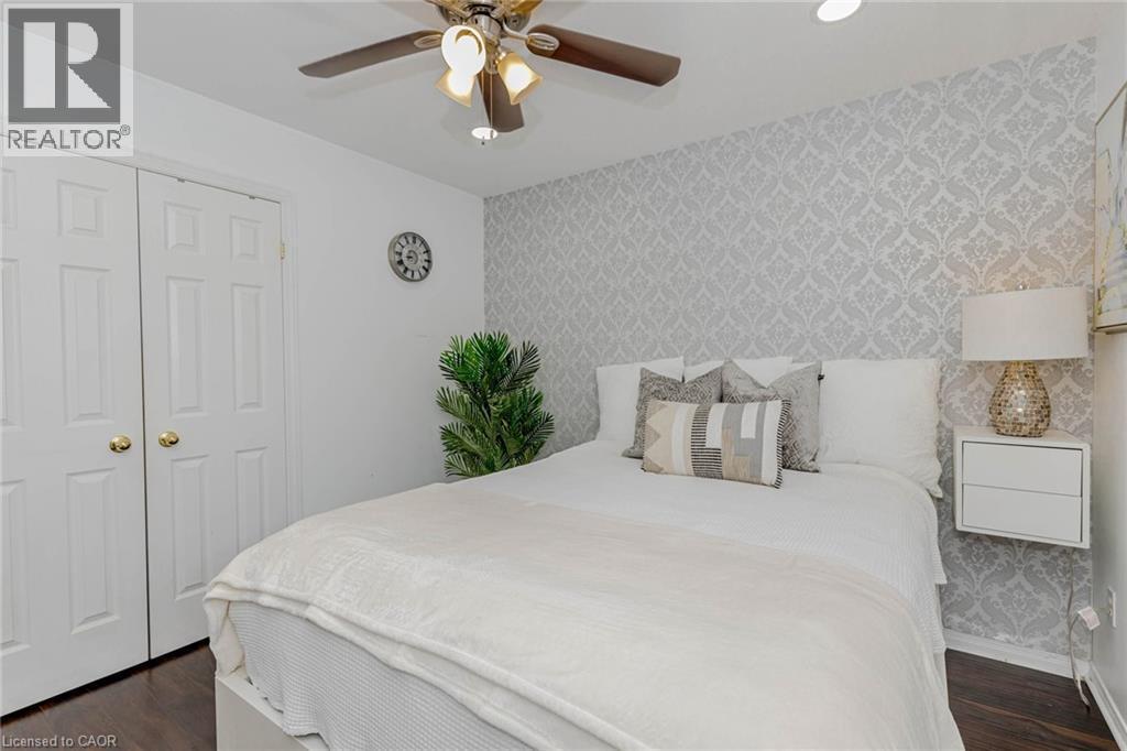 Bedroom featuring wallpapered walls, an accent wall, ceiling fan, dark wood-type flooring, and a closet - 32 Vineberg Drive, Hamilton, ON - Indoor Photo Showing Bedroom