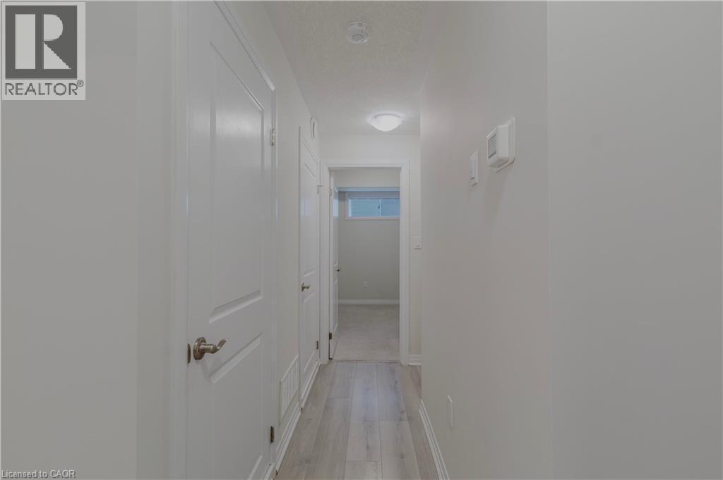 Corridor with a textured ceiling, light wood finished floors, and baseboards - 25 Isherwood Avenue Unit# G-105, Cambridge, ON - Indoor Photo Showing Other Room