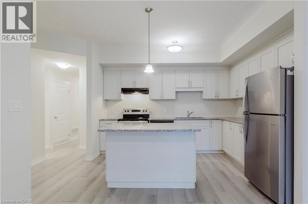 Kitchen with stainless steel appliances, under cabinet range hood, light wood-type flooring, and a sink - 25 Isherwood Avenue Unit# G-105, Cambridge, ON - Indoor Photo Showing Kitchen With Stainless Steel Kitchen With Upgraded Kitchen