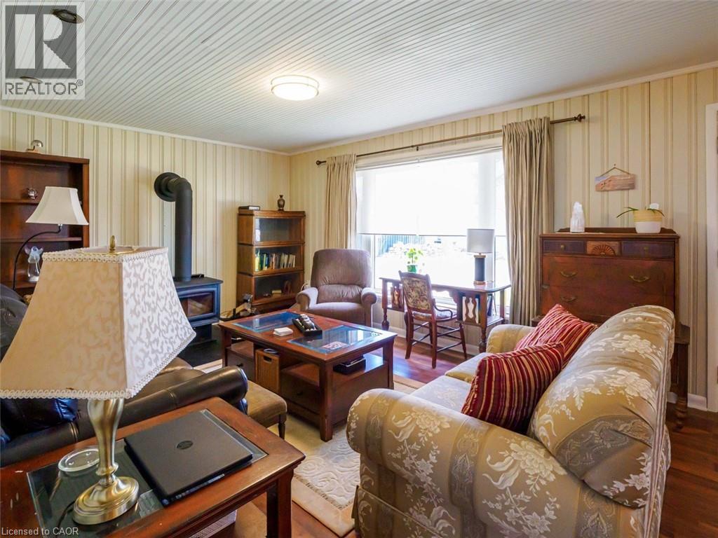 Living area featuring a freestanding wood-burning stove, and a large picture window looking out to the lake. - 1395 Lakeshore Road, Haldimand County, ON - Indoor Photo Showing Living Room With Fireplace