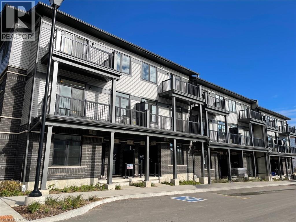 Modern multi-level building featuring a combination of brick and siding, private balconies with dark railings, and ground-floor patio spaces - 26 Wheat Lane, Kitchener, ON - Outdoor