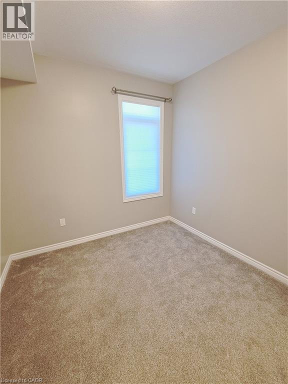 Carpeted room with a single window featuring horizontal blinds and a decorative curtain rod - 26 Wheat Lane, Kitchener, ON - Indoor Photo Showing Other Room