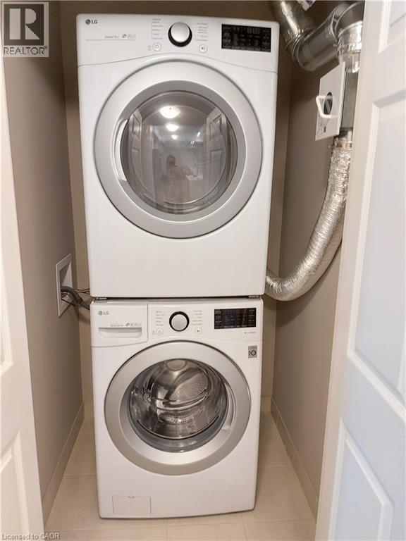 Dedicated laundry alcove featuring a stacked washer and dryer unit, compact design, tile flooring, and neutral wall finishes - 26 Wheat Lane, Kitchener, ON - Indoor Photo Showing Laundry Room