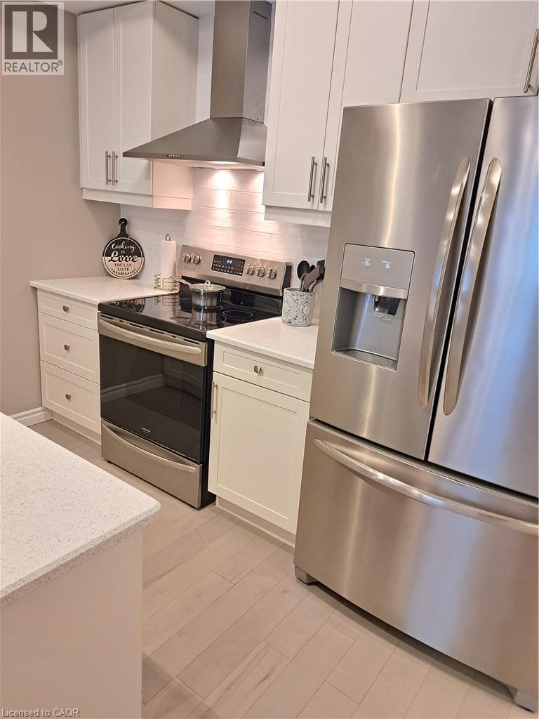 Modern kitchen featuring white shaker cabinetry, quartz countertops, a stainless steel appliance suite, and wood-finish flooring - 26 Wheat Lane, Kitchener, ON - Indoor Photo Showing Kitchen