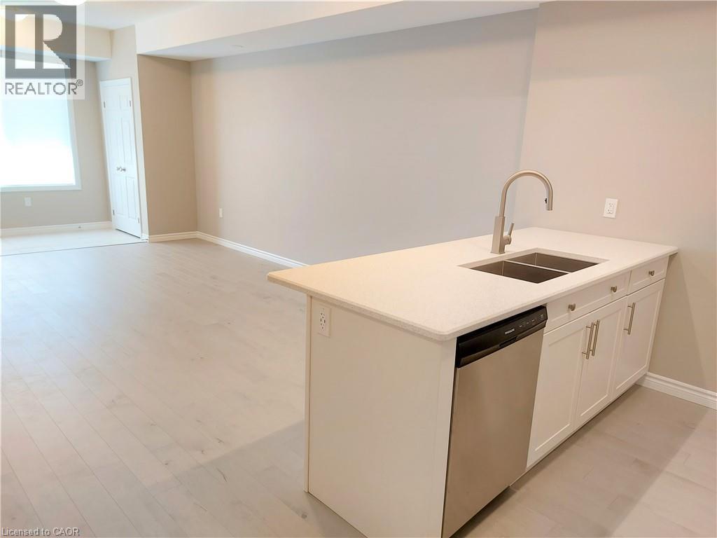 Kitchen island featuring a double basin sink with a gooseneck faucet, light-toned countertop, and integrated stainless steel dishwasher - 26 Wheat Lane, Kitchener, ON - Indoor Photo Showing Kitchen With Double Sink